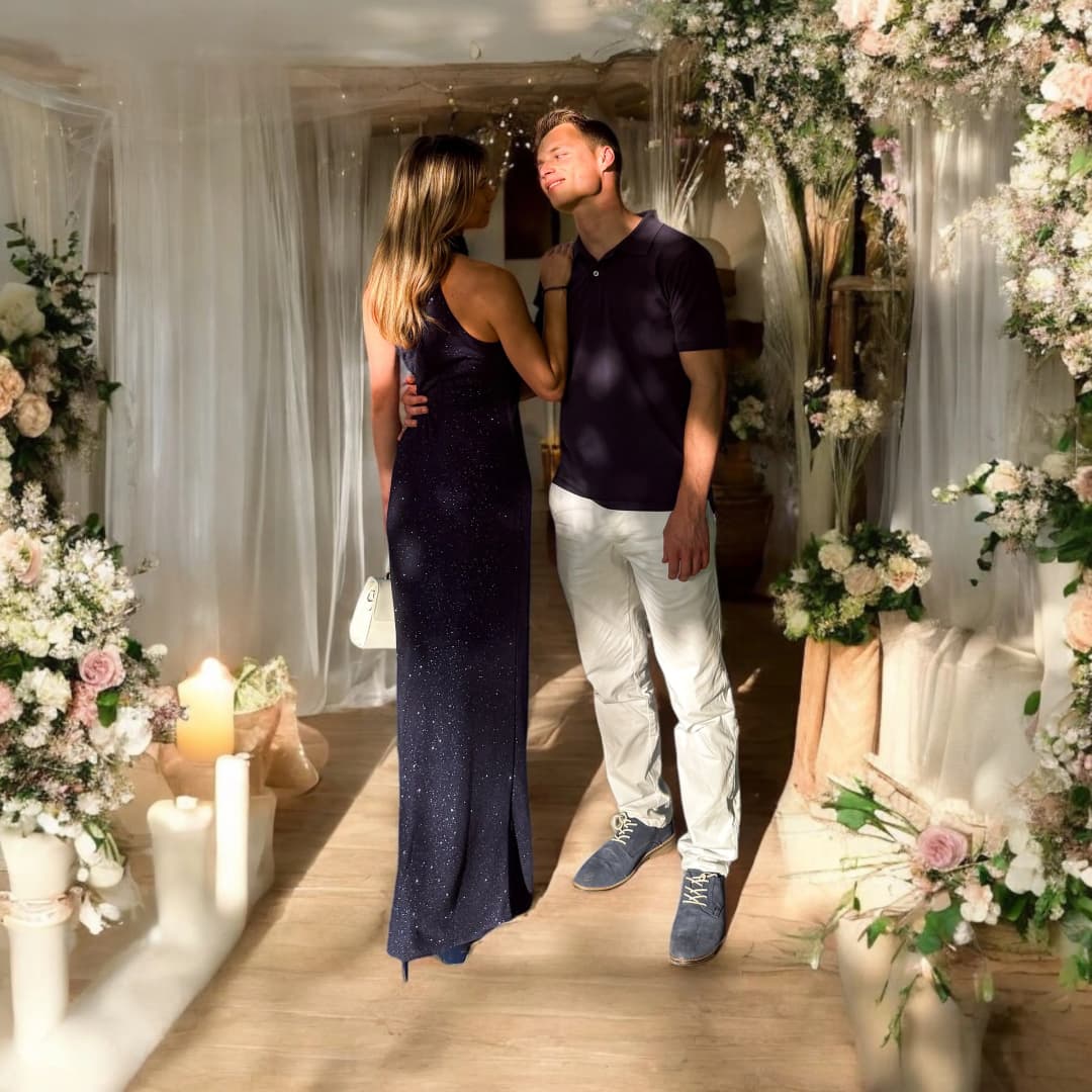 Couple face à face entre des bougies et des fleurs, elle en robe longue bleu marine pailletée, lui en haut bleu marine et pantalon blanc